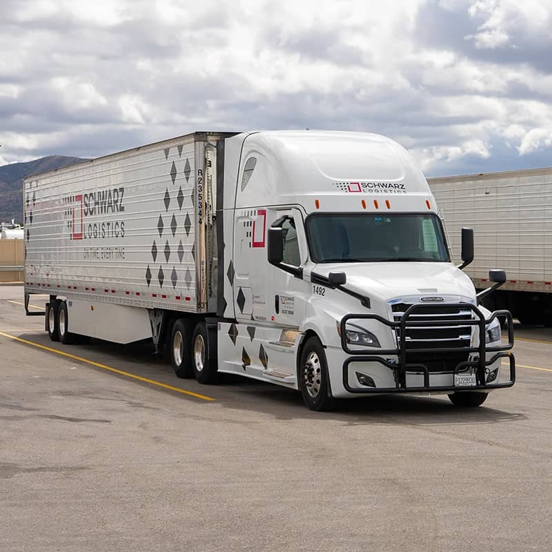 Schwarz Logistics semi truck with reefer trailer parked at a truck stop.