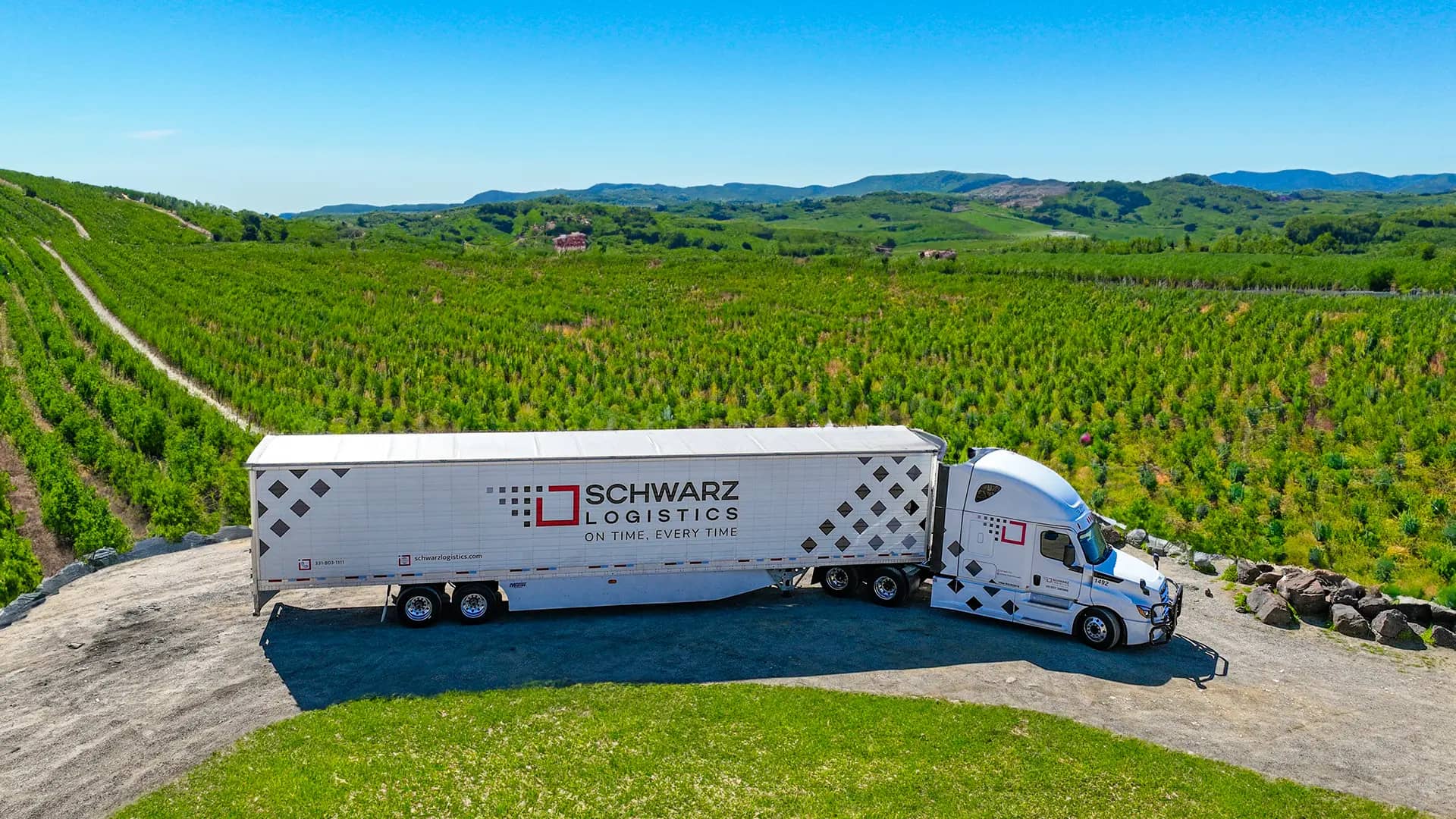 Schwarz Logistics reefer truck with an apple orchard on the background.